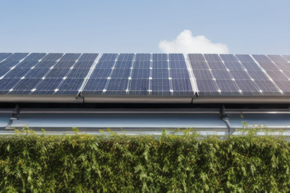Imagem de um prédio sustentável com paredes verdes e painéis solares no telhado
